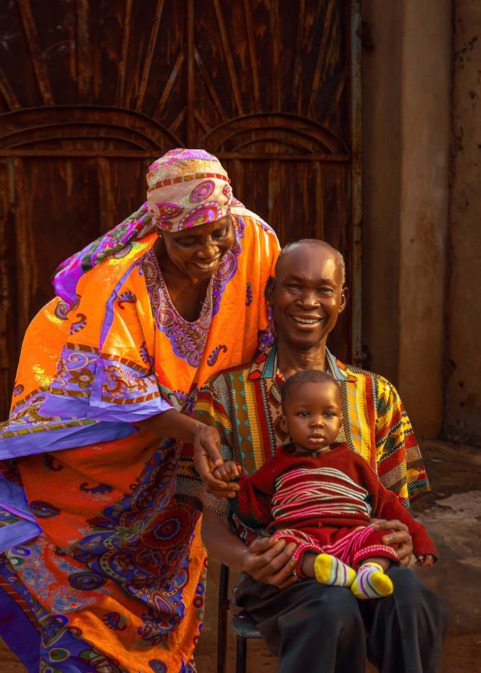 Smiling African family dressed in vibrant traditional clothing, sharing a joyful moment outdoors in Nigeria.