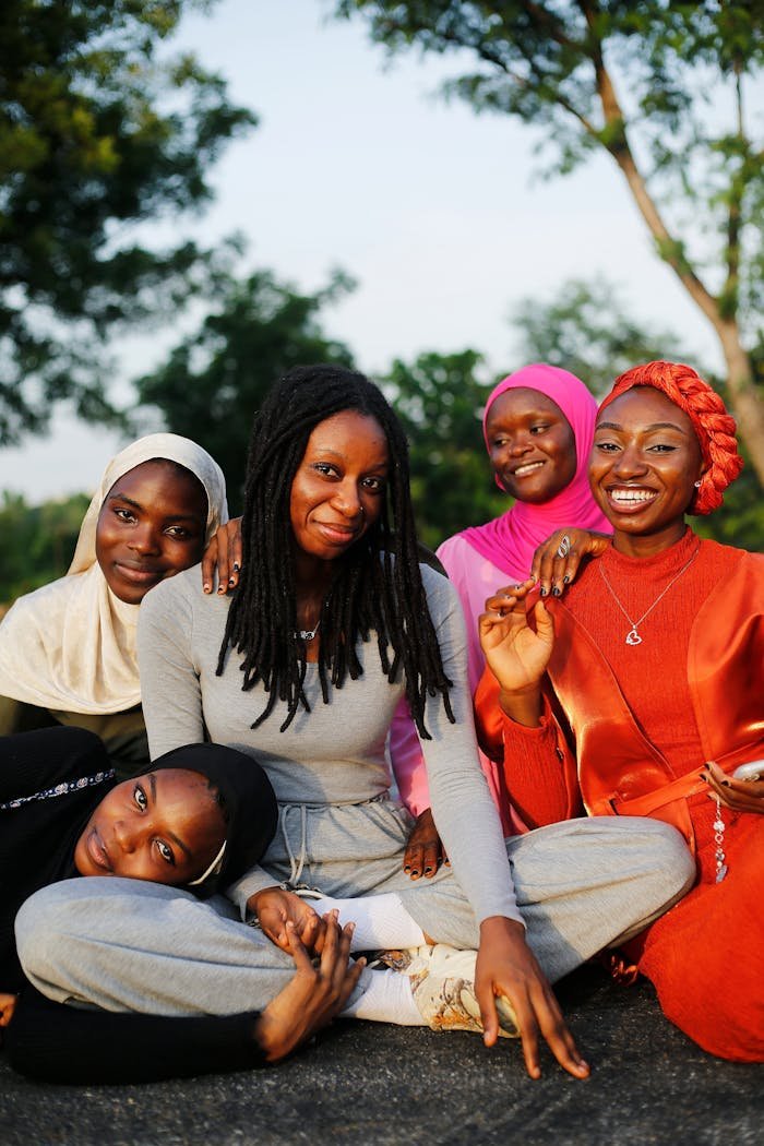 Five smiling women sitting outdoors in Abuja, embracing and posing for a photo.