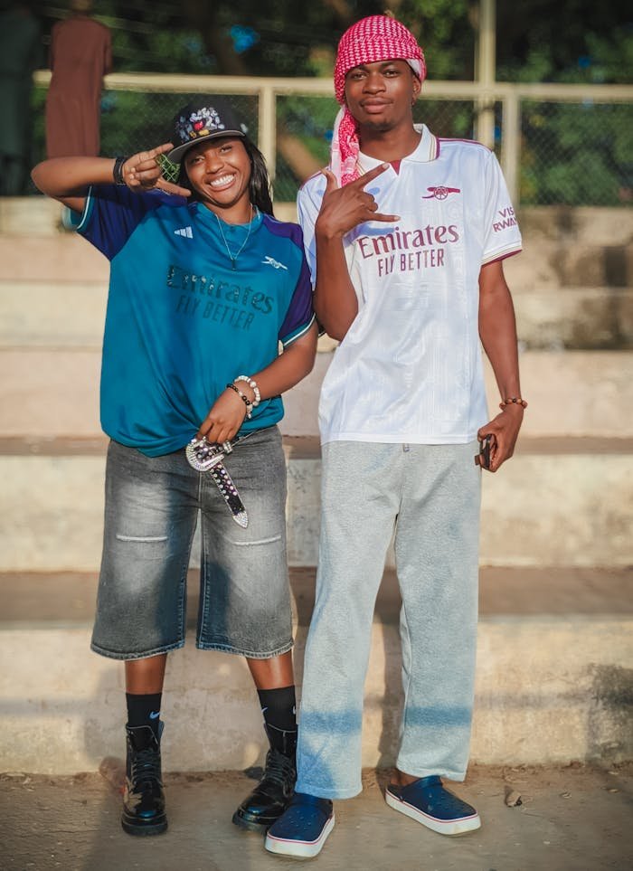Smiling young adults in sports jerseys posing outdoors on steps.