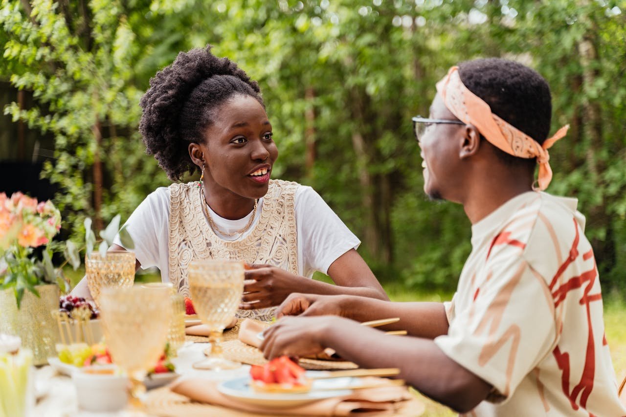 A couple enjoys a vibrant outdoor meal surrounded by nature, sharing laughter and conversation.